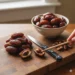 The Sweet Secret Revealed: How Dates Are Pitted For Ultimate Convenience 8 Hand Using A Chopstick To Pit A Medjool Date Next To A Knife And A Bowl Of Whole Dates.