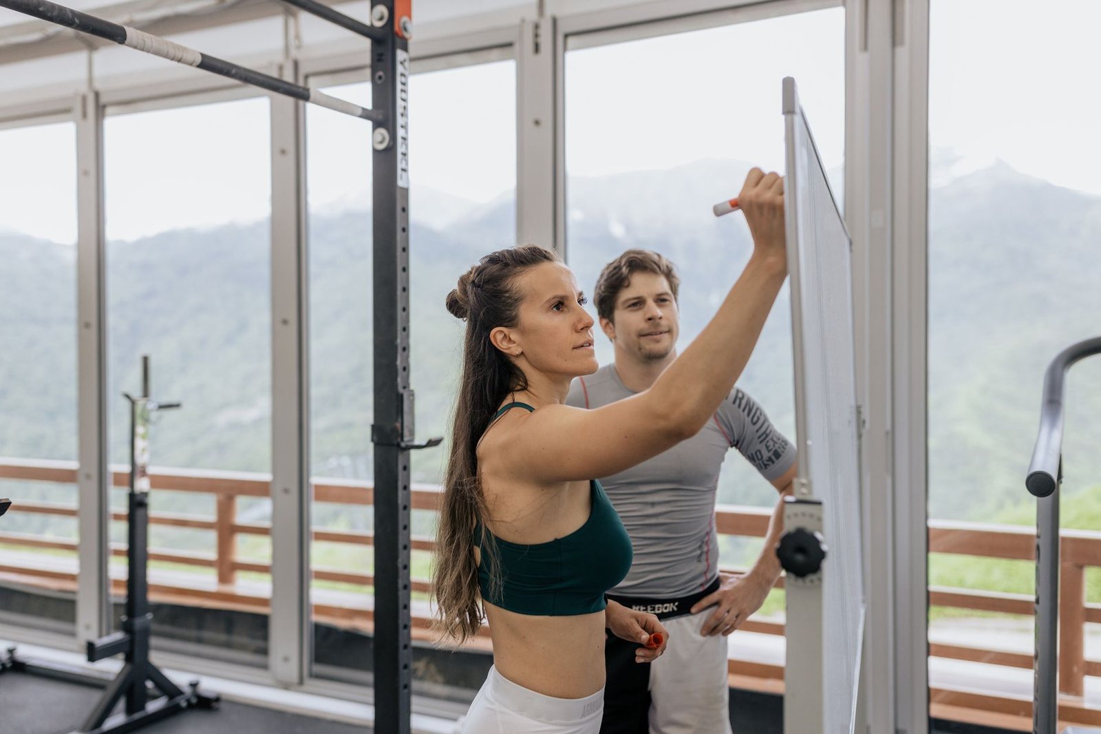 Hybrid athlete training equipment featuring dumbbells and running shoes in a modern gym setting.